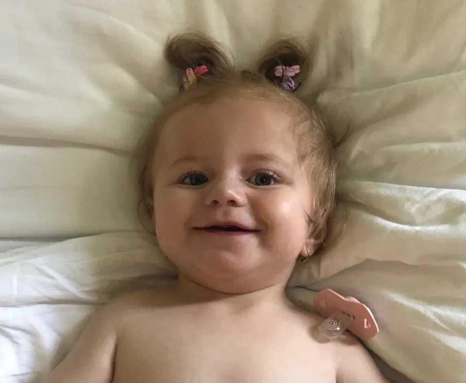 Eliška se usmívá, leží v posteli s dvěma culíčky