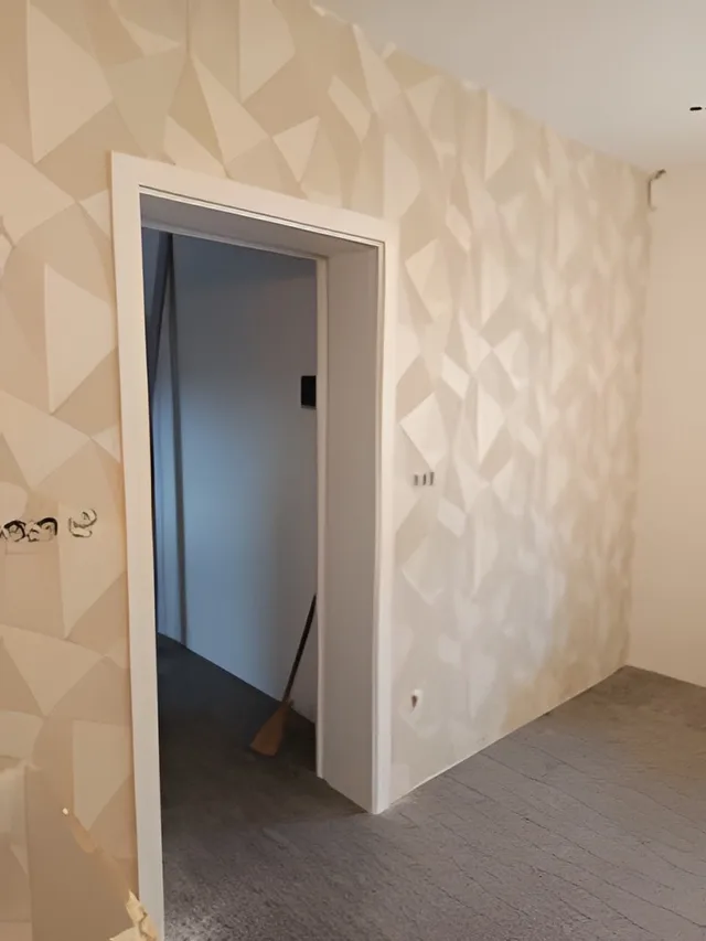 Chodba s béžově šedou geometrickou tapetou s trojúhelníky kolem dveří